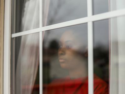 women in red shirt looking outside window