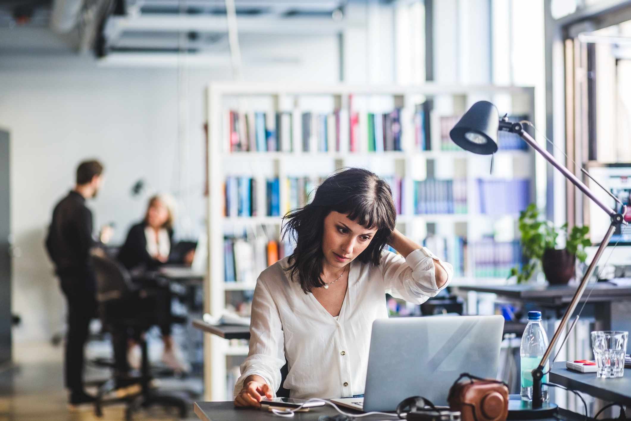 A woman working at her desk in a busy office.