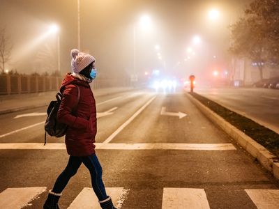 woman wearing a mask walking in a polluted city