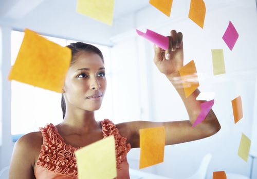 woman looking at sticky notes on glass wall