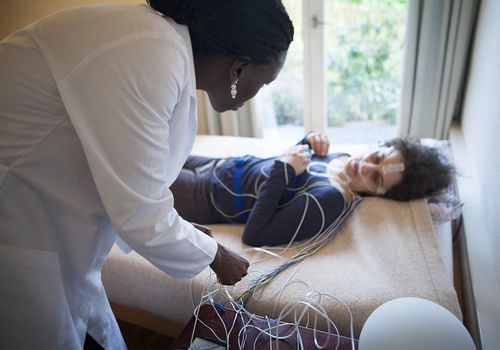 woman being hooked up to sleep study machinery