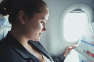 在飞机上看新闻的女商人。