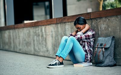 一个人坐在地板上，靠在他们旁边的背包。