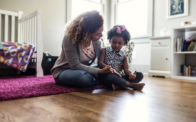 母亲坐在地板上使用与一个幼儿。