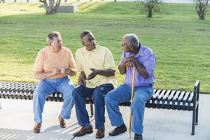 三个不同种族的高级男子坐在长椅上聊天