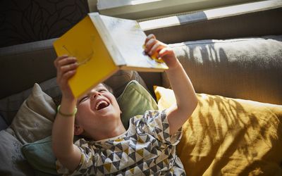 男孩躺着看书笑
