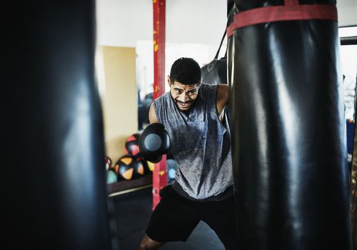 male boxer punching heavy bag in gym