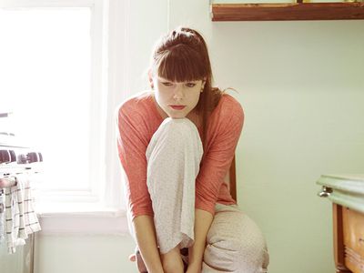 Young Woman Sitting In Kitchen Alone