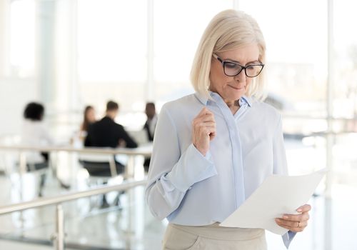 Anxious woman reading notes outside an office full of people