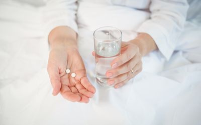 女人在床上用水服药