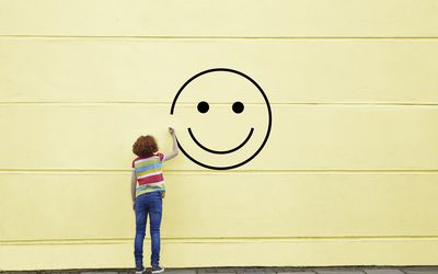 在黄色墙上画笑脸的女人