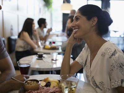 微笑对男朋友，吃和饮用的酒的妇女在咖啡馆桌上
