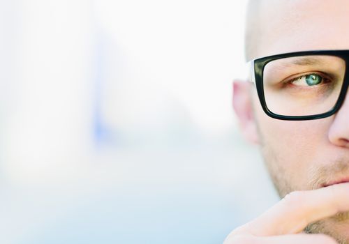 A man wearing dark glasses looking thoughtfully off in the distances.