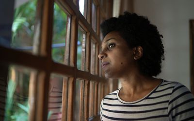 BIPOC immigrant looking out window