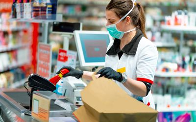 工作在杂货店的妇女佩带防护面具