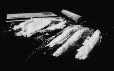 可卡因特写镜头与卷起的纸币和信用卡在黑背景