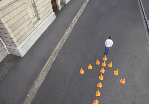 Man standing in front of traffic cones in arrow-shape