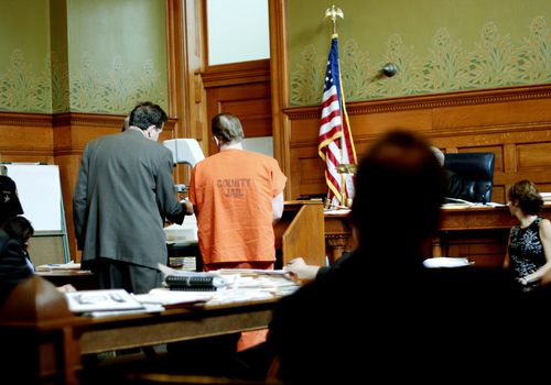 Attorney and defendant in a county jail jumpsuit in a courtroom