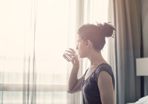 Young woman drinking water in the bedroom