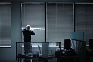 商人透过紧闭的百叶窗看