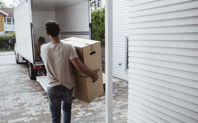 男子扛着纸板箱走向货车的后视图