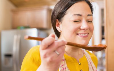 用木勺品尝酱汁的女人