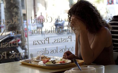 独自吃的哀伤的妇女在咖啡馆
