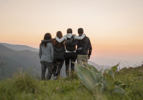 group of hikers standing on viewpoint at sunset