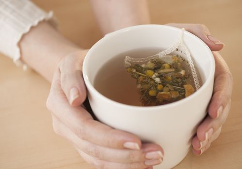 Woman holding cup with chamomile tea