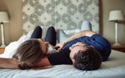 这是一对快乐的年轻夫妇在家里的卧室里分享浪漫时刻的照片