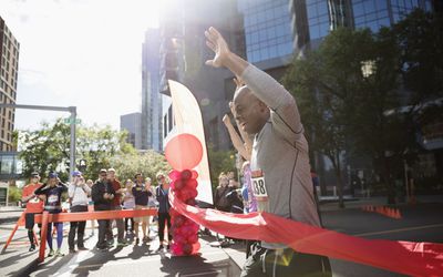 精力充沛的男性马拉松运动员举起双臂越过终点线