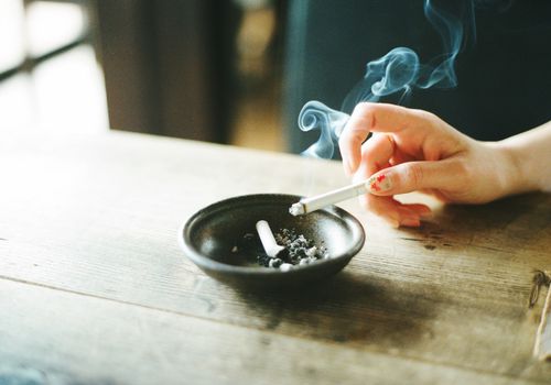 女人的手拿着香烟在烟灰缸上