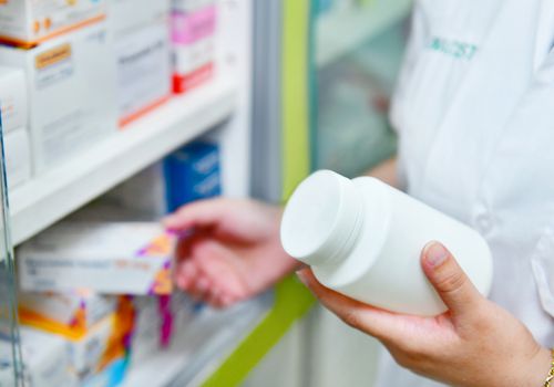 Pharmacist holding bottle and box of medicine