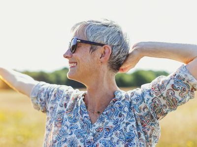 有胳膊的热情的资深妇女在晴朗的领域伸出