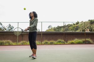 Young woman with racquet and ball on tennis court
