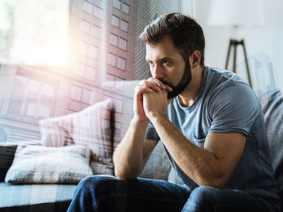 Think about it. Thoughtful serious beardful man sitting in the empty room holding hands near mouth and thinking.
