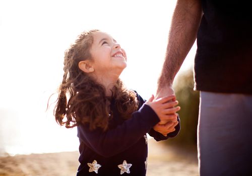 young smiling girl holding a man's hand