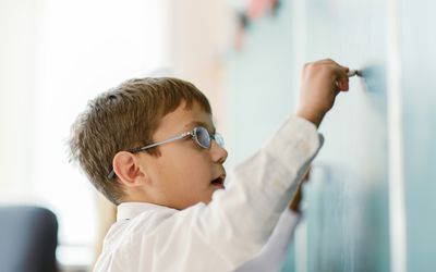 Schoolboy writing on chalk board