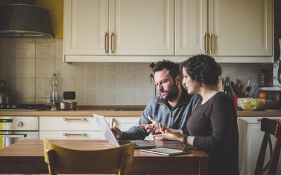 一对夫妇坐在桌子旁，用笔记本电脑