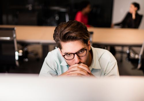 Young man thinking in front of computer