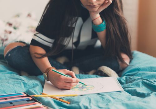 年轻女子在床上用彩色铅笔着色