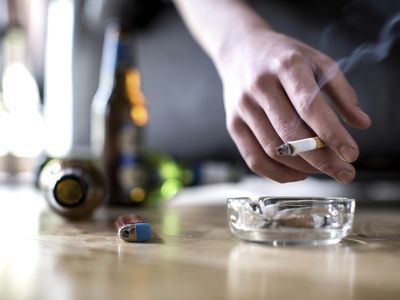 一个拿着香烟，地上放着啤酒瓶的男人