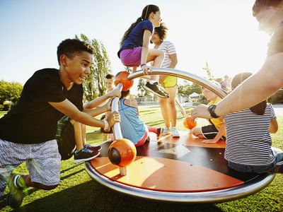 Group of kids playing on merry go round on playground