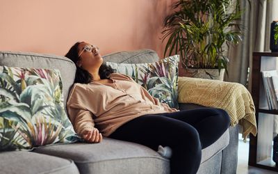 一个压力过大的女人扑通一声倒在灰色的沙发上，张开双臂，望着天花板。