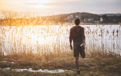 在冰冻的湖边伸展的人