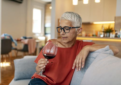 Mature woman sitting on the couch with a glass of wine