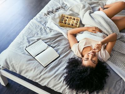 拿着巧克力和日记躺在床上的BIPOC女人
