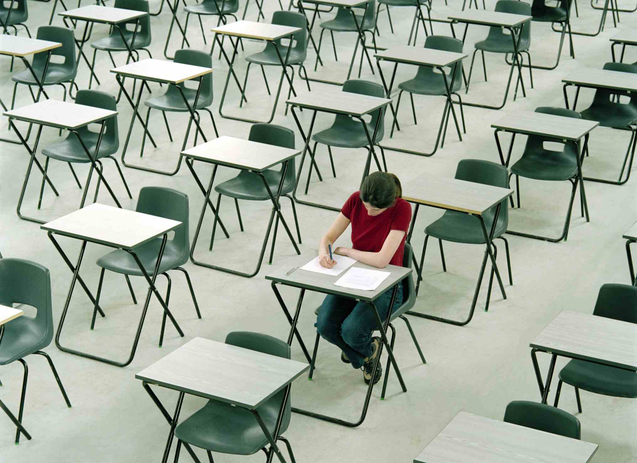 坐在许多空课桌中间的学生