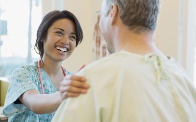 安慰男性患者的愉快的女性护士在诊所