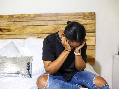 person sitting on bed looking distressed